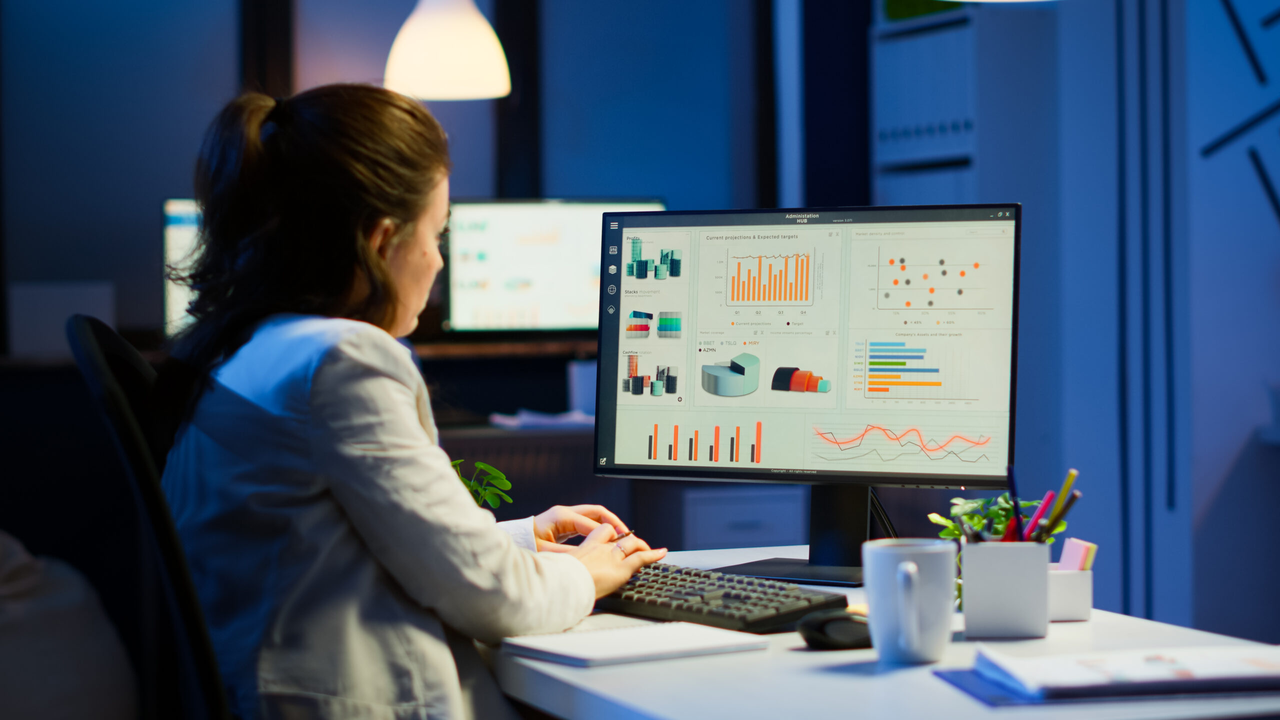 Busy woman working at night in front of computer taking notes